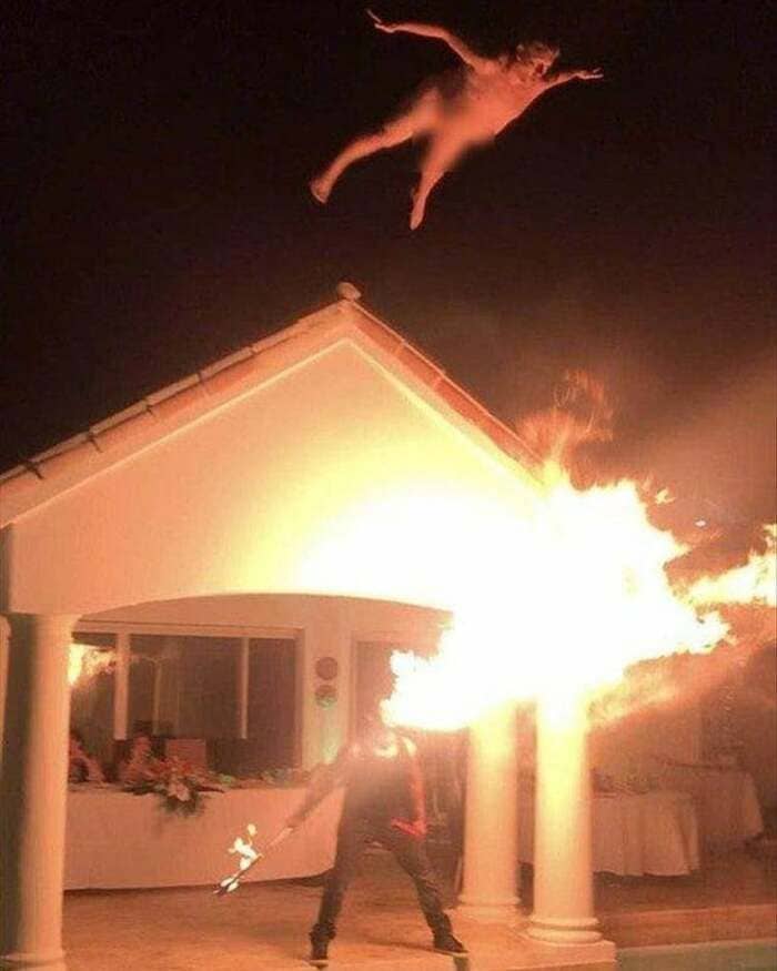 man jumping over fire, man jumping over fire into pool, man leaping over fire into pool, man flying over fire into pool, funny cursed image, cursed image