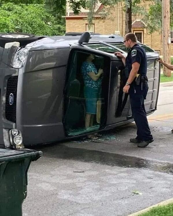 accidental surrealism - car on its side with a woman standing up talking to police