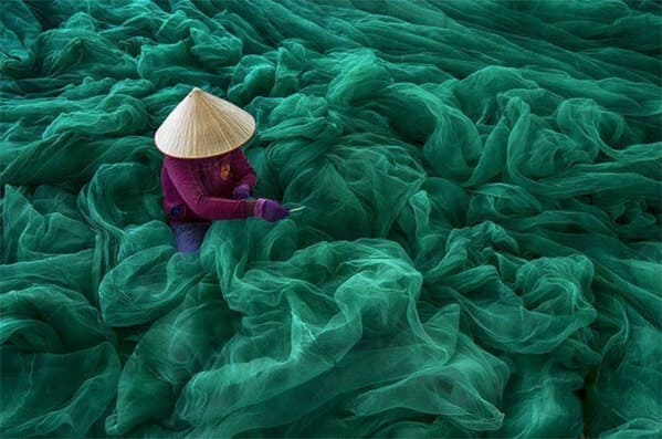accidental surrealism - woman repairing fish nets