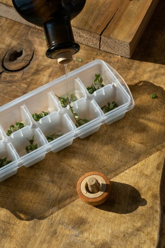 A Close-Up Shot of Water being Poured into an Ice Cube Tray with Herbs