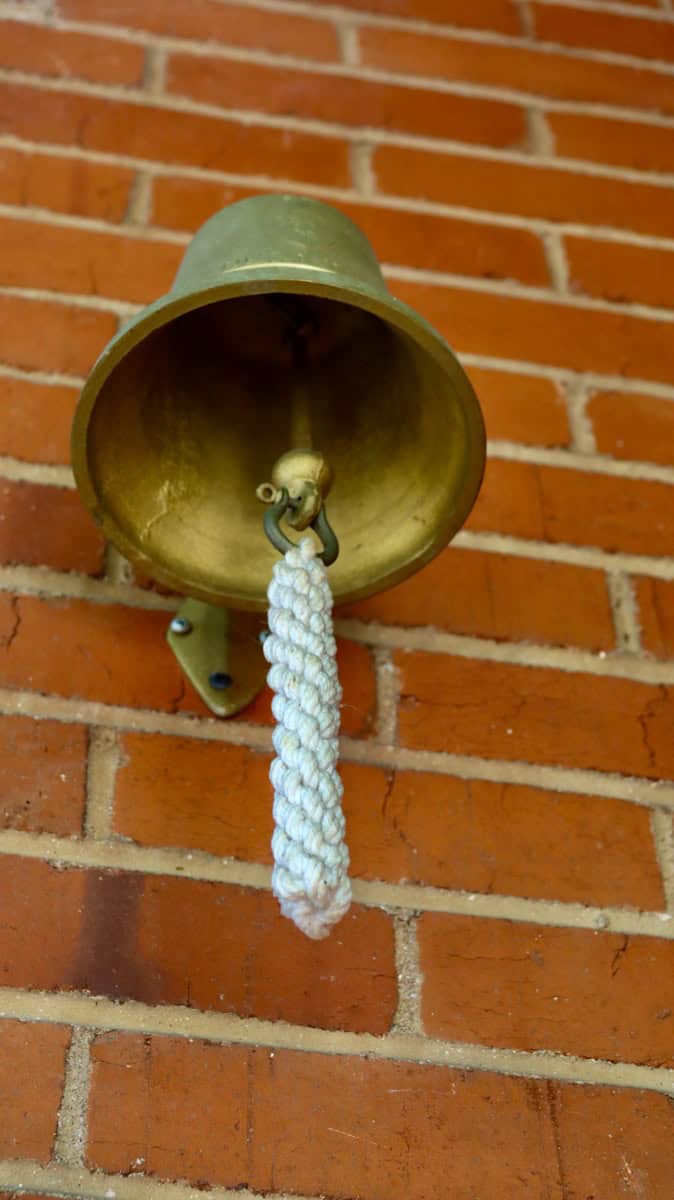 brass bell on brown brick wall