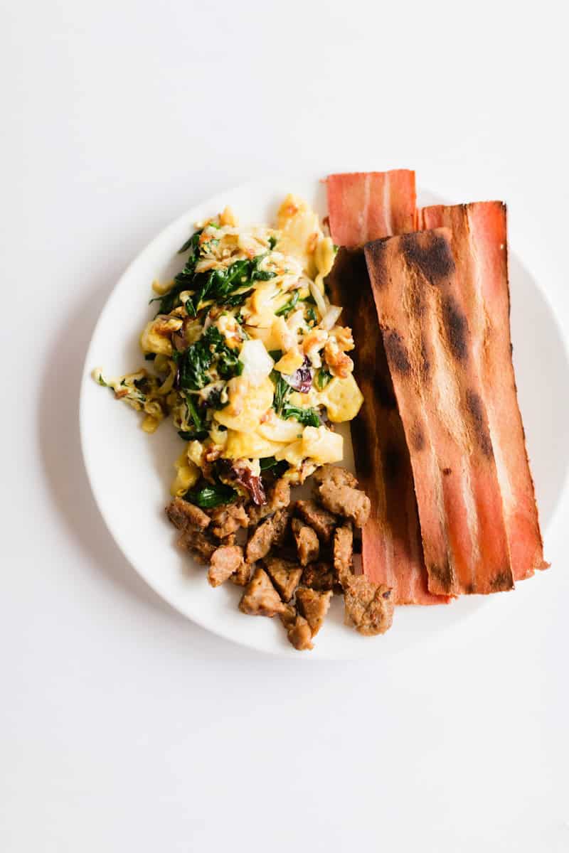 a white plate topped with bacon and eggs