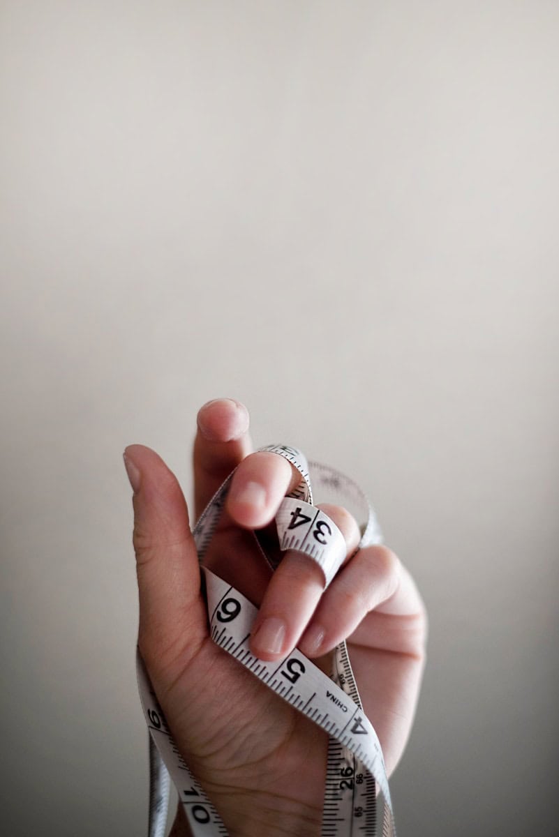 person's left hand wrapped by tape measure