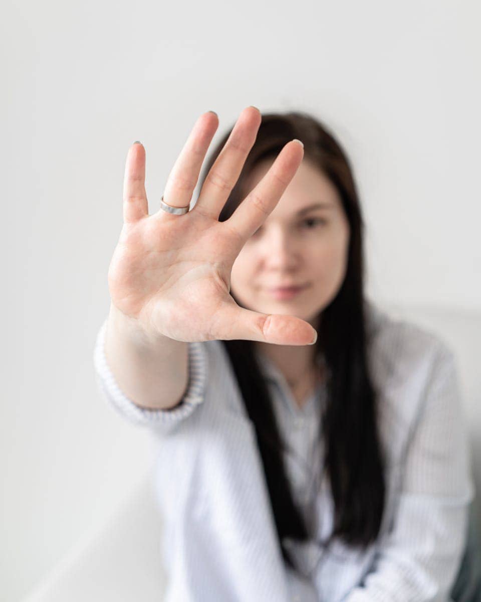 Female extending hand forward with a blurred face for a focused perspective indoors.