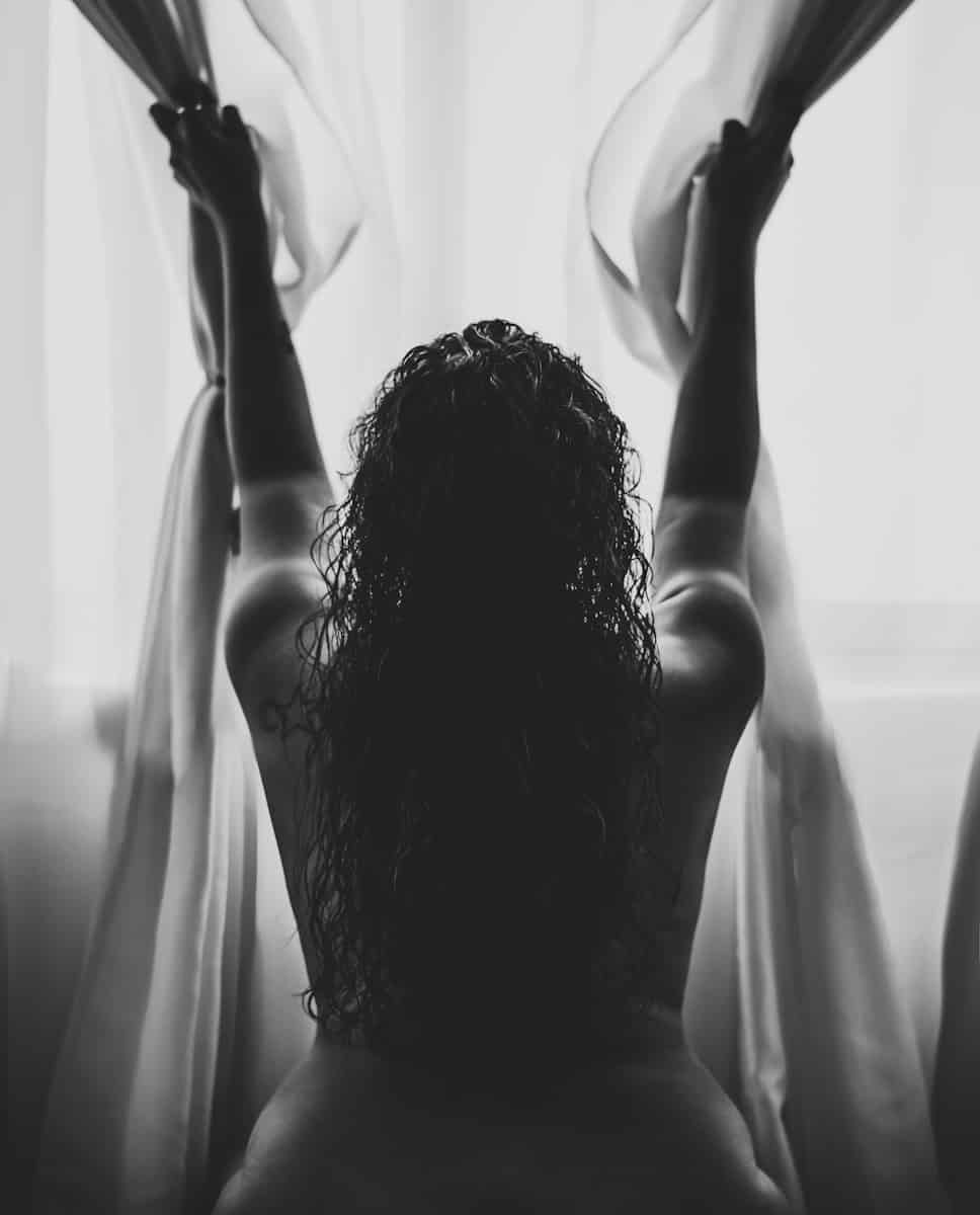 naked woman clinging on curtain