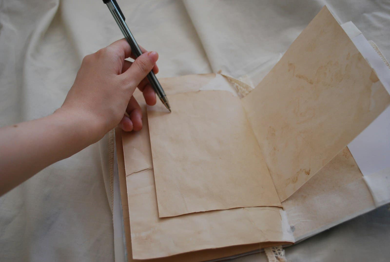 A person holding a pen and writing on a piece of paper