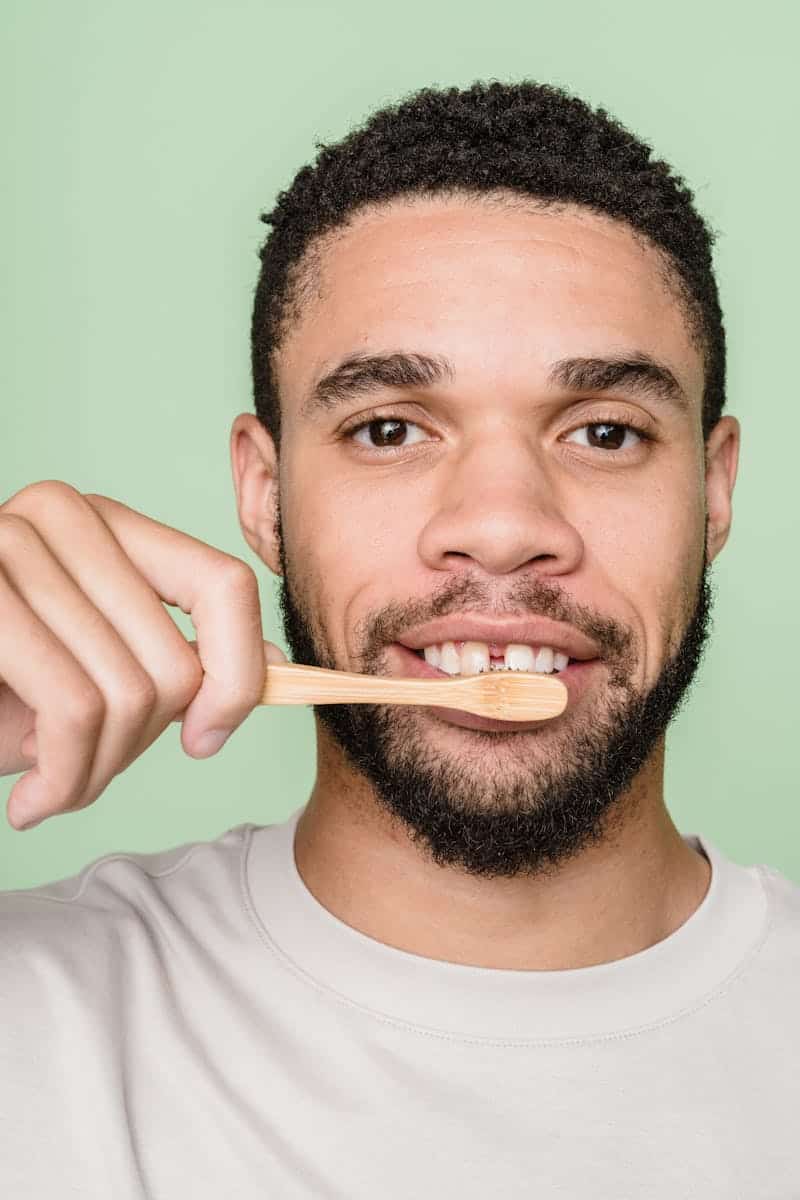 Close-up portrait of a man brushing teeth with a bamboo toothbrush, promoting sustainability.