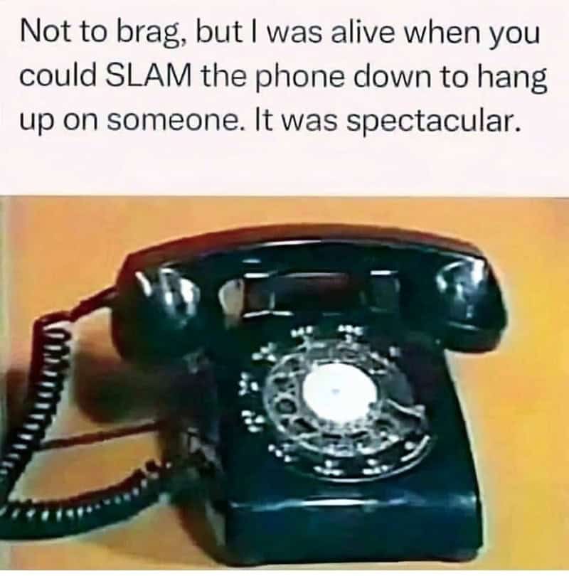 Classic black rotary phone on wooden surface, vintage communication device.