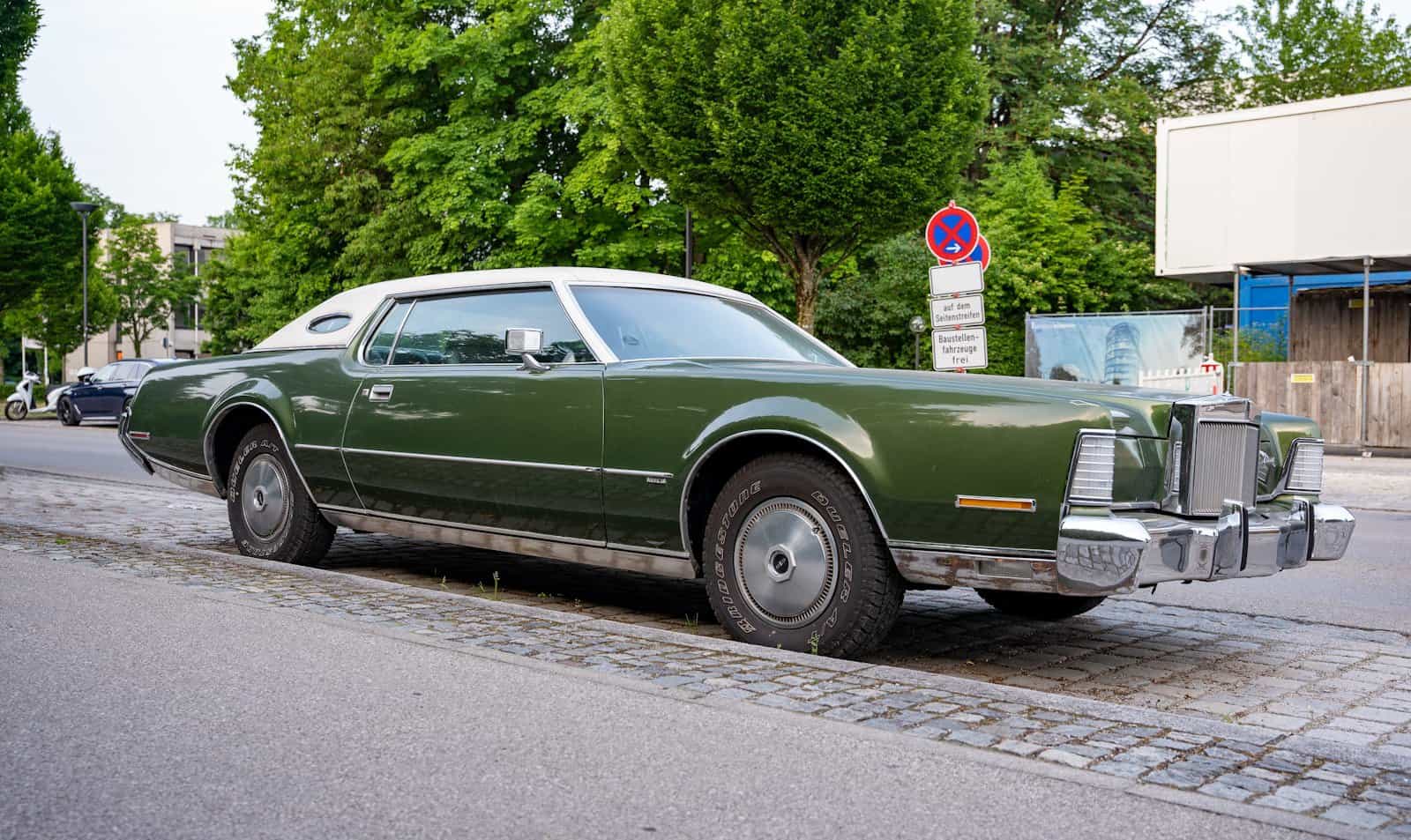 green sedan on gray asphalt road during daytime