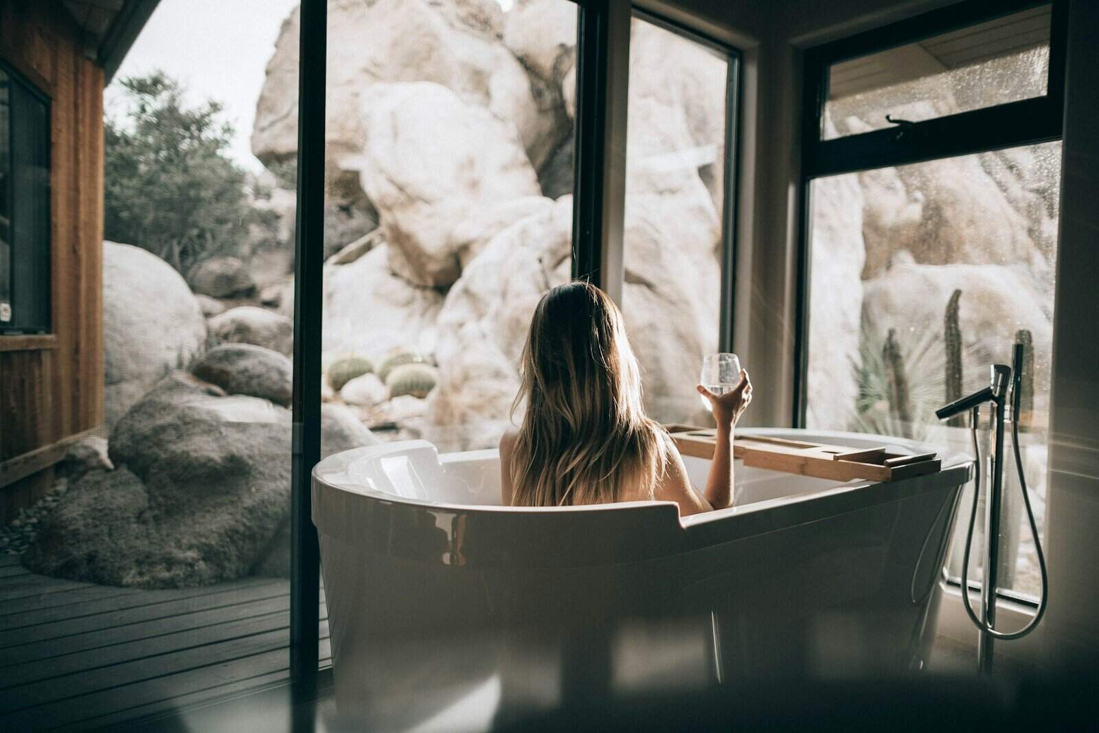 Femme en baignoire blanche tenant du verre à boire clair