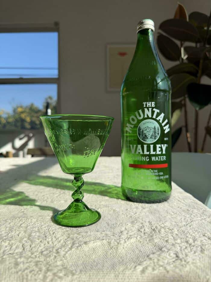 Eco-friendly Mountain Valley bottled spring water and matching green glass cup.