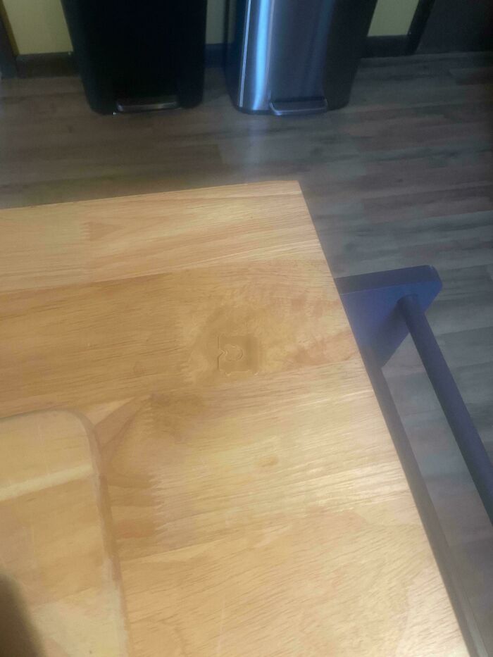 Wooden dining table with a black chair in a modern kitchen environment.