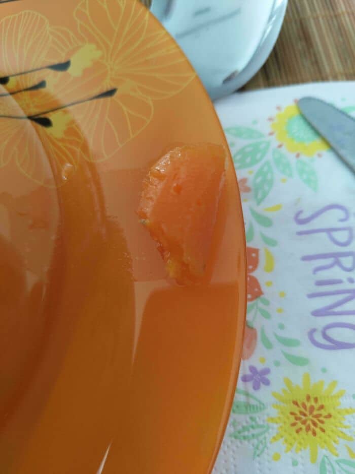 Orange fruit slice on decorative plate with spring-themed napkin and utensils in background.