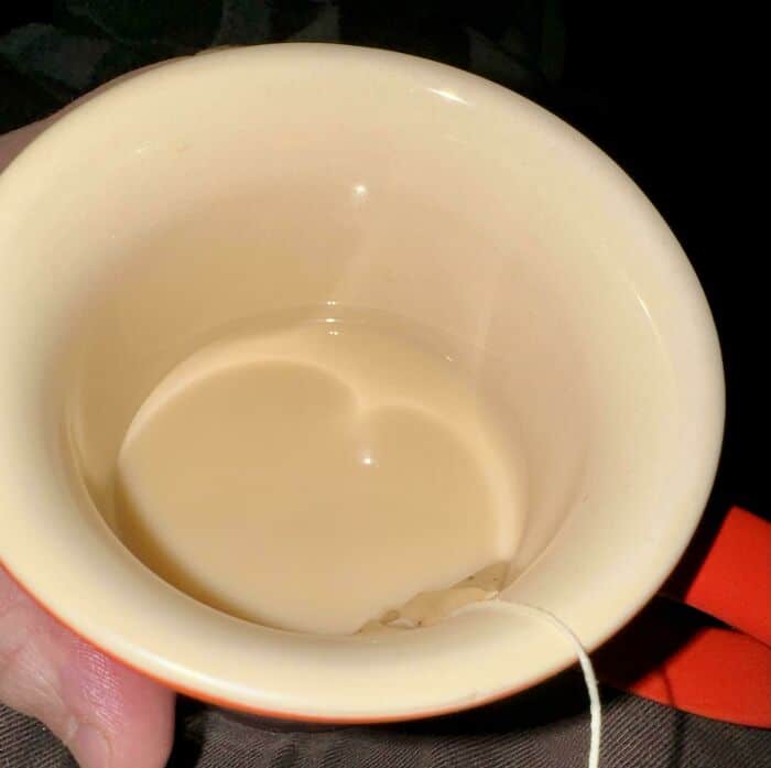 Coffee mug with tea bag inside, top view.
