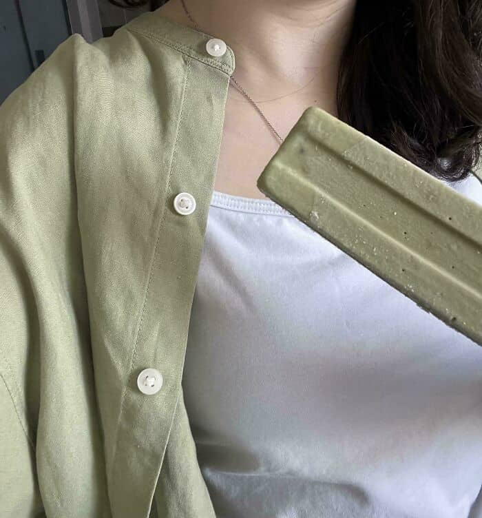 Woman in casual outfit holding a popsicle, close-up of her upper body and clothing.