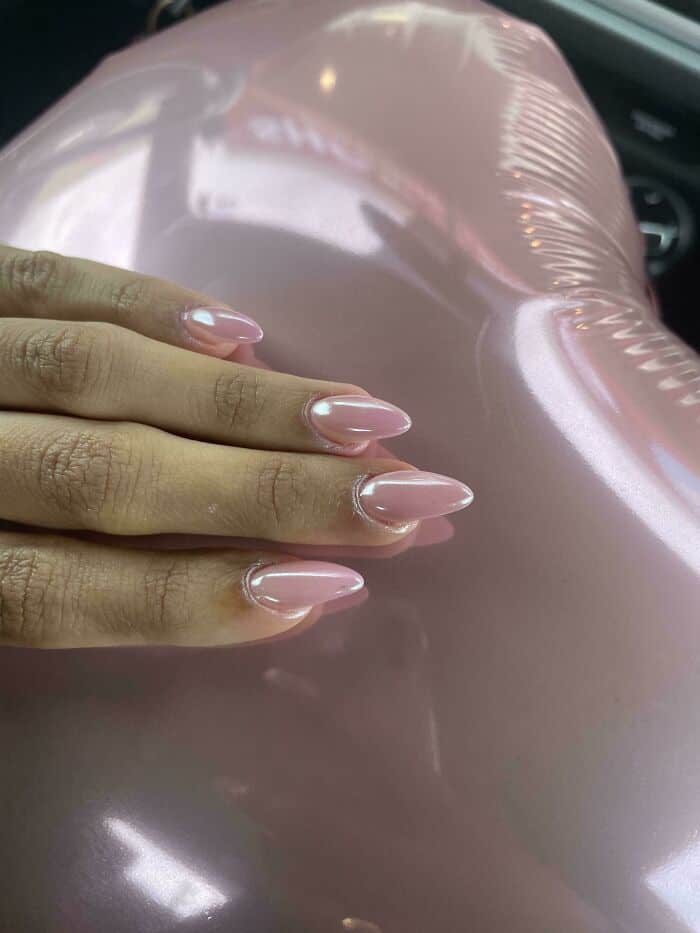 Shiny pink balloon with a hand resting on it, close-up shot.