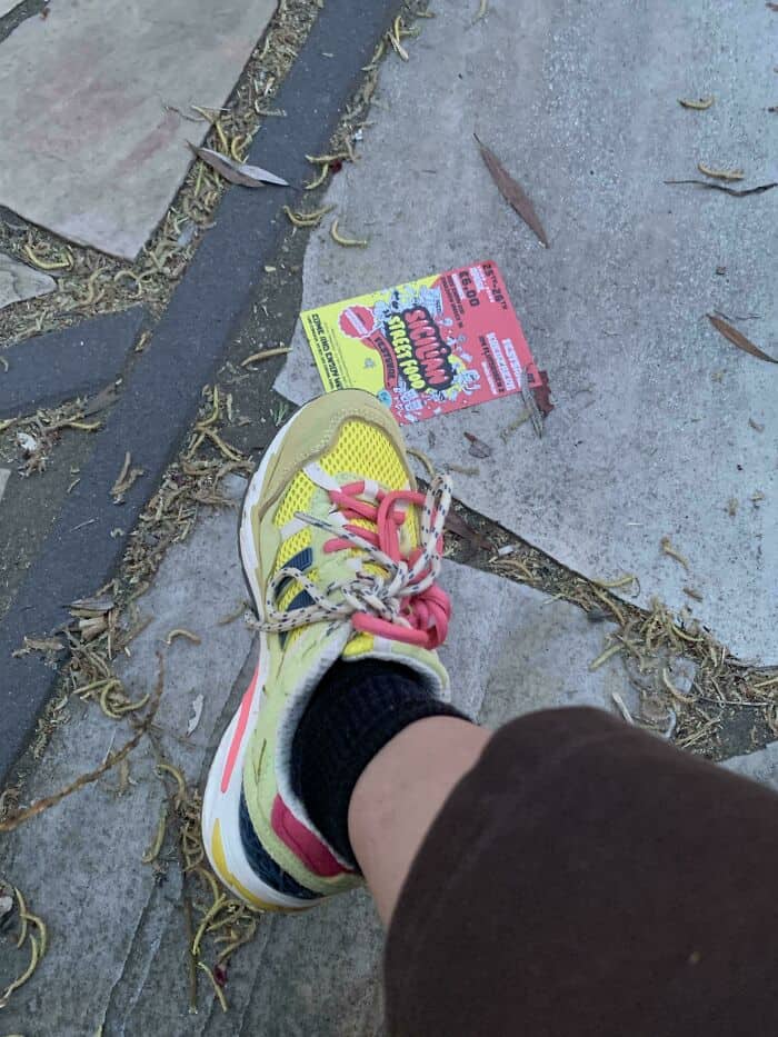 Close-up of colorful sneaker on sidewalk with flyer and leaves.