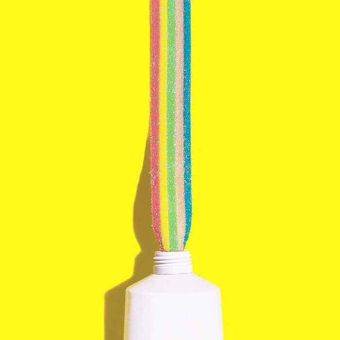 A playful and surreal image of rainbow candy flowing from a white bottle, blending humor and creativ.