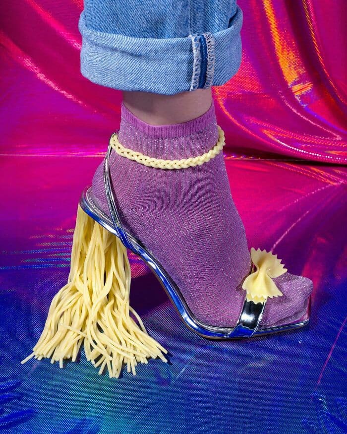 Unique surreal shoe with pasta heel and purple sock.