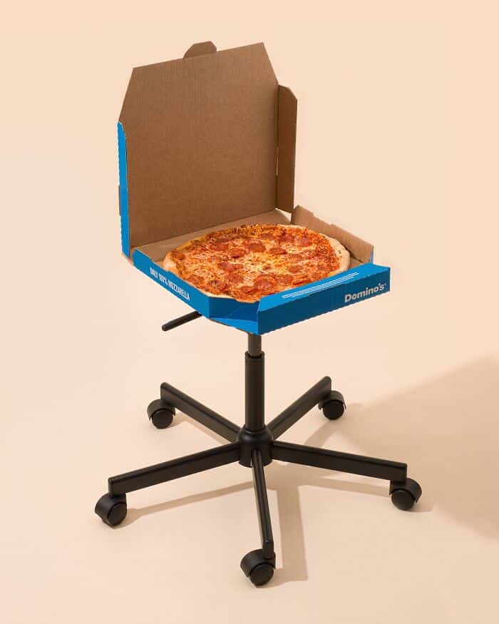 Pizza box chair on a rolling office chair base, blending surrealism and humor.