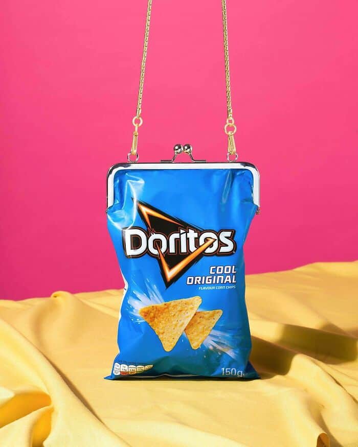 Blue Doritos bag used as a purse with chain strap on pink background.