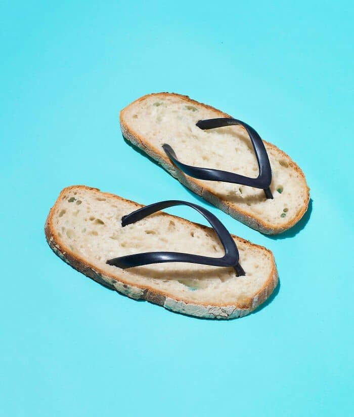 Slice of bread with black sunglasses on a bright blue background.