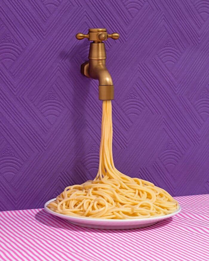Creative spaghetti flowing from a faucet against a purple wall.
