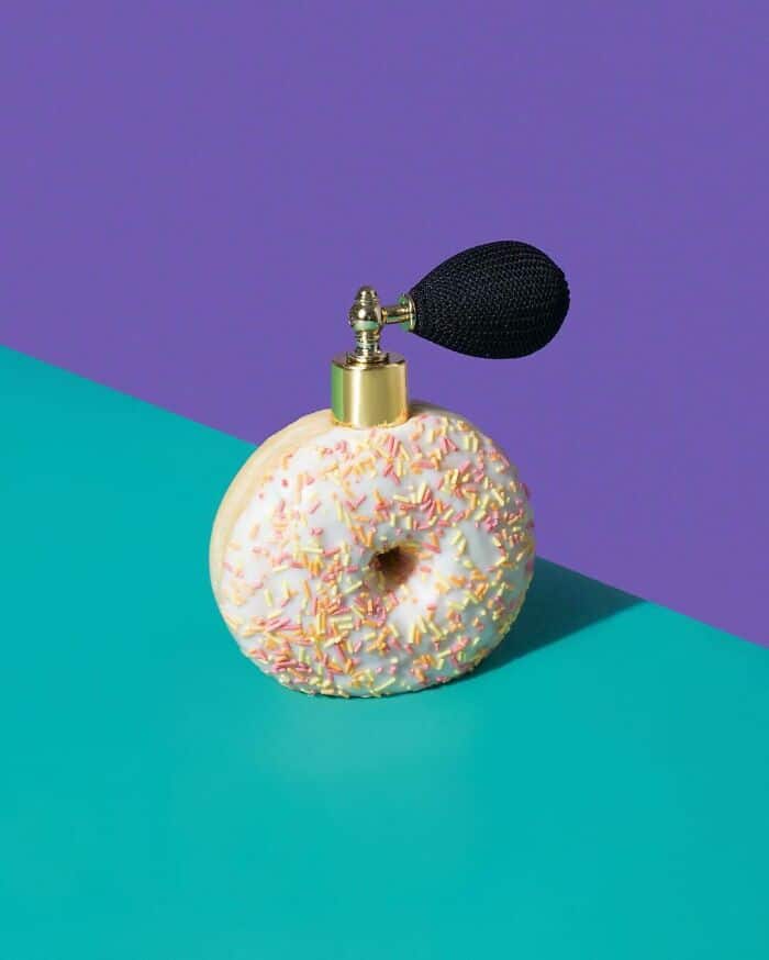 Whimsical perfume bottle designed as a donut with colorful sprinkles and a black atomizer, set again.