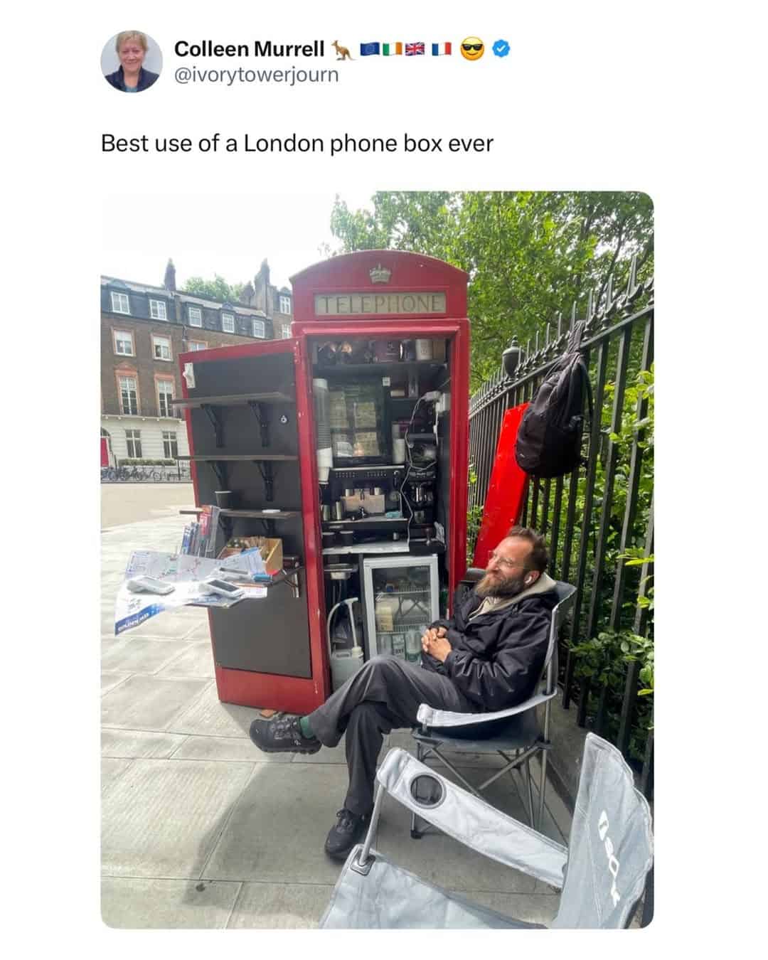 Iconic red London phone box repurposed as a free Wi-Fi station with a man sitting outside.