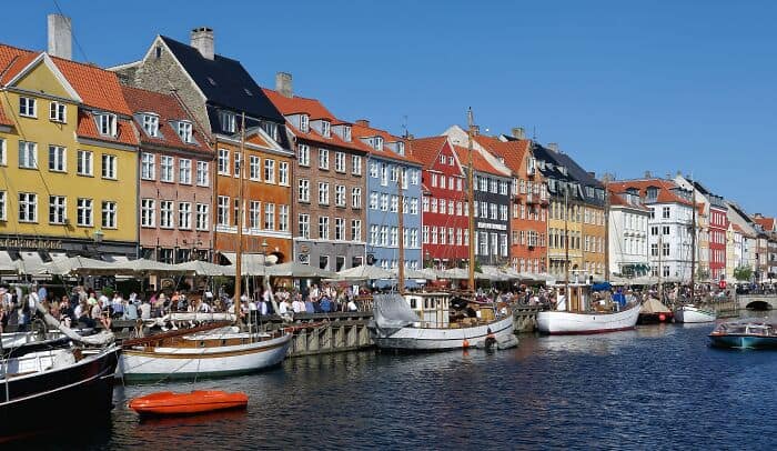 Colorful waterfront buildings along a canal with boats in a lively city scene.