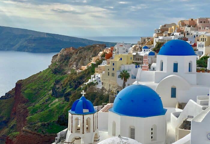 Scenic view of Santorini with white buildings and blue domes overlooking the sea.