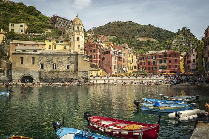 Vibrant seaside town with colorful buildings, boats, and scenic hillside backdrop.
