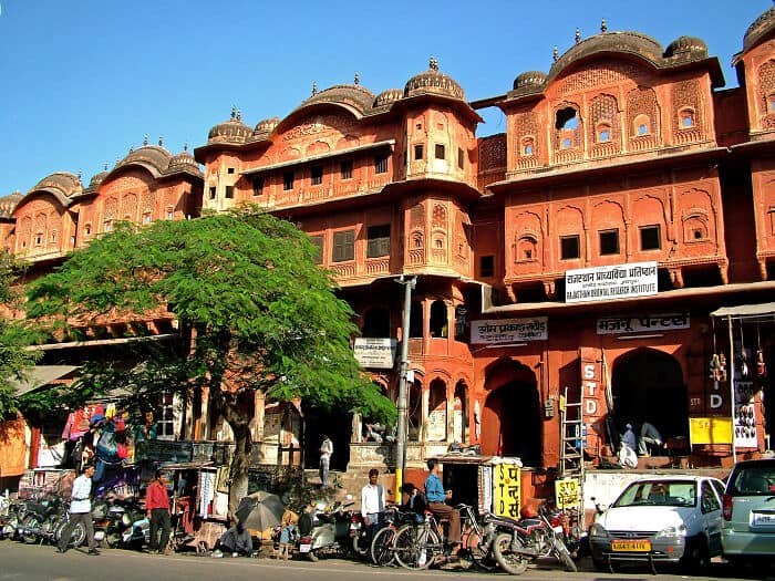 Colorful, traditional Indian architecture with vibrant red hues and intricate designs. Busy street s.