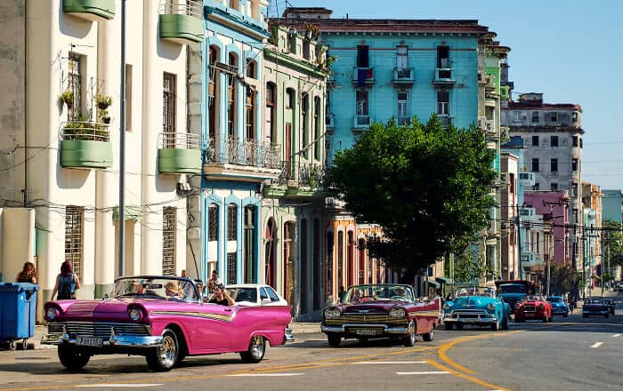 Vibrant Havana street scene with classic cars and colorful colonial architecture.