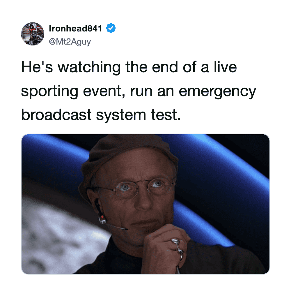 Man with headset watching a sports event on a screen.