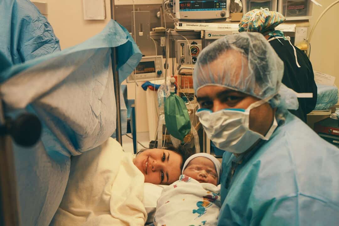 Medical team with mother and newborn in hospital delivery room.