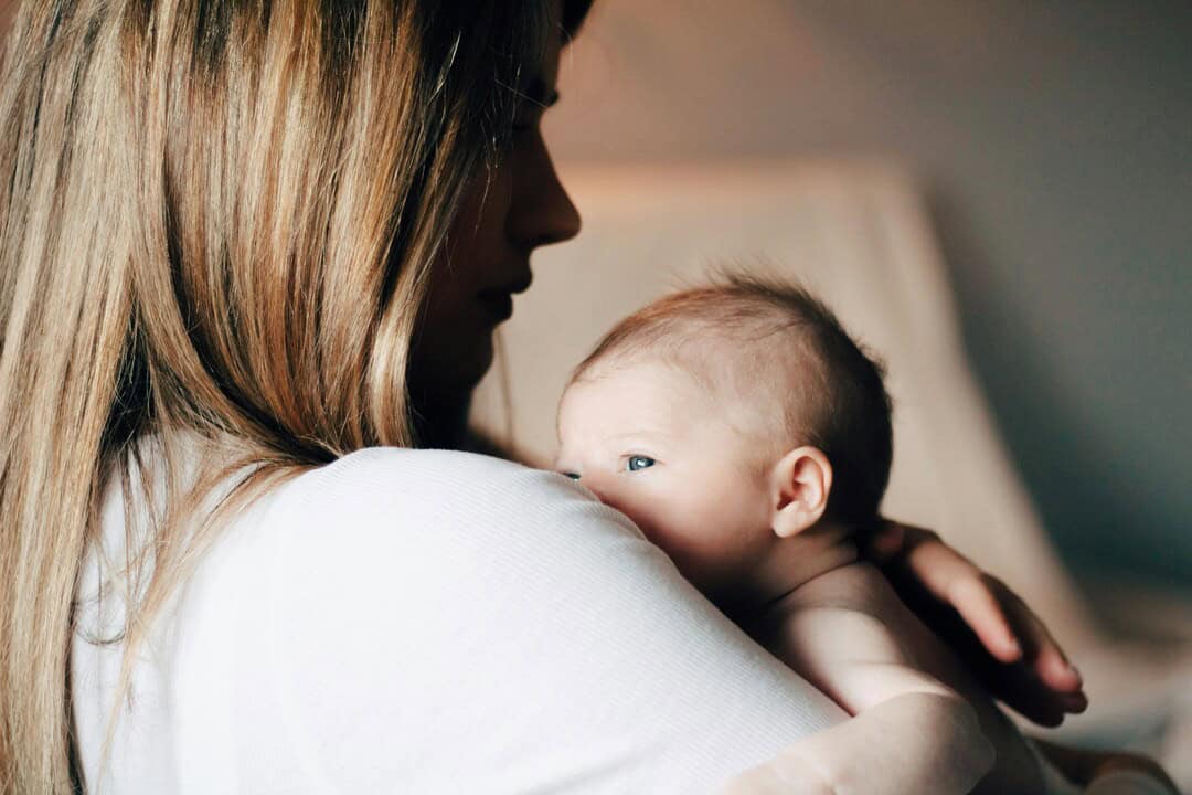 Mother holding her baby, tender moment, emotional connection, family love, caring parent, infant bon.