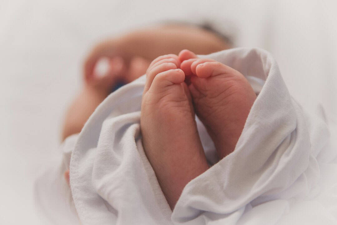 Baby's hands gently clasped in sleep, showcasing innocence and tenderness.