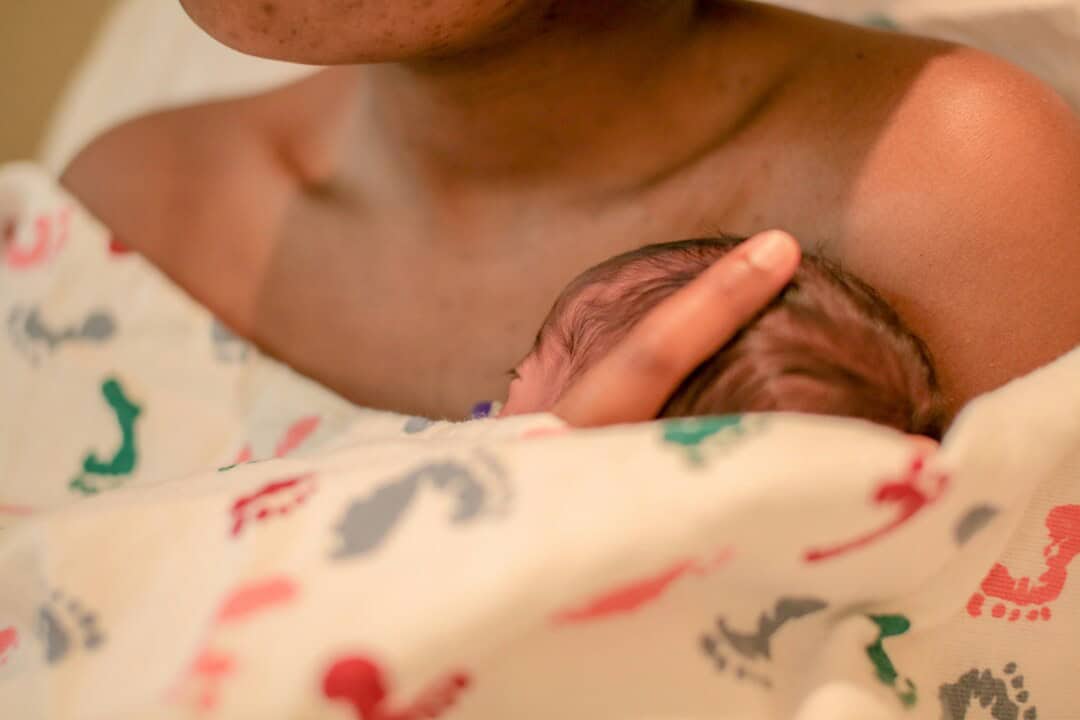 Close-up of mother holding newborn baby, emphasizing maternal bond and tenderness.