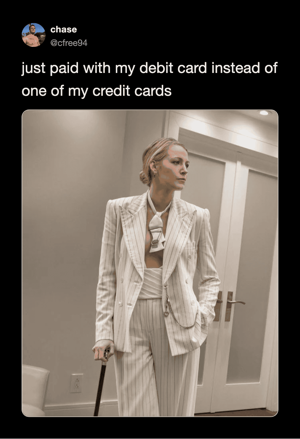 Woman in stylish pinstripe suit holding cane, standing indoors.