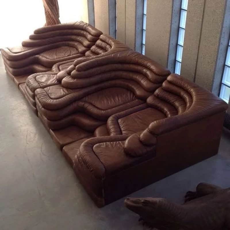 Large brown leather sectional sofa with plush cushions in a modern living room setting.