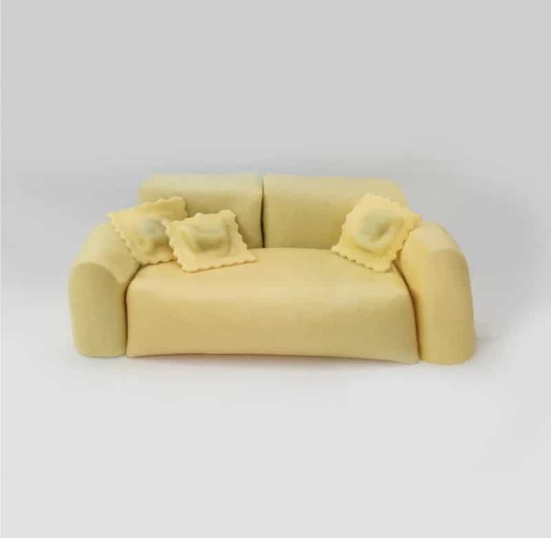 Small yellow sofa with two matching pillows on a plain white background.