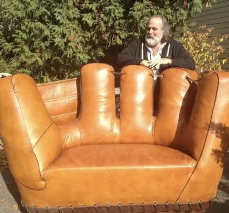 Large vintage leather sofa outdoors with a man sitting behind it, enjoying a sunny day.