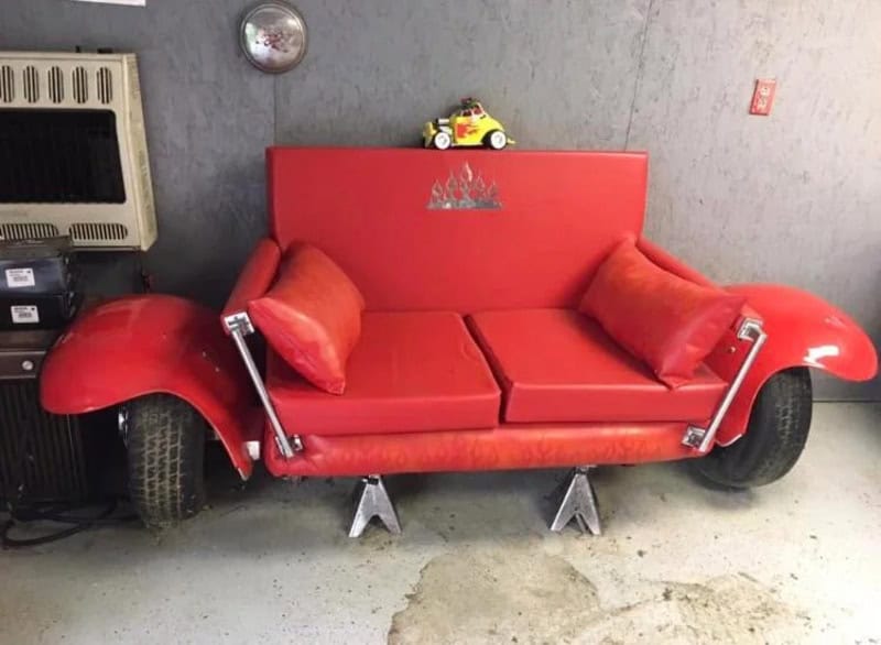 Unique car-themed sofa with red upholstery and tire wheel accents.