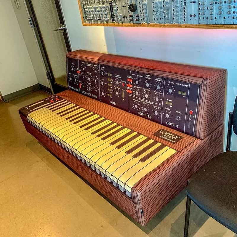 Vintage Moog synthesizer keyboard with wooden finish and control panel, placed in a music studio.