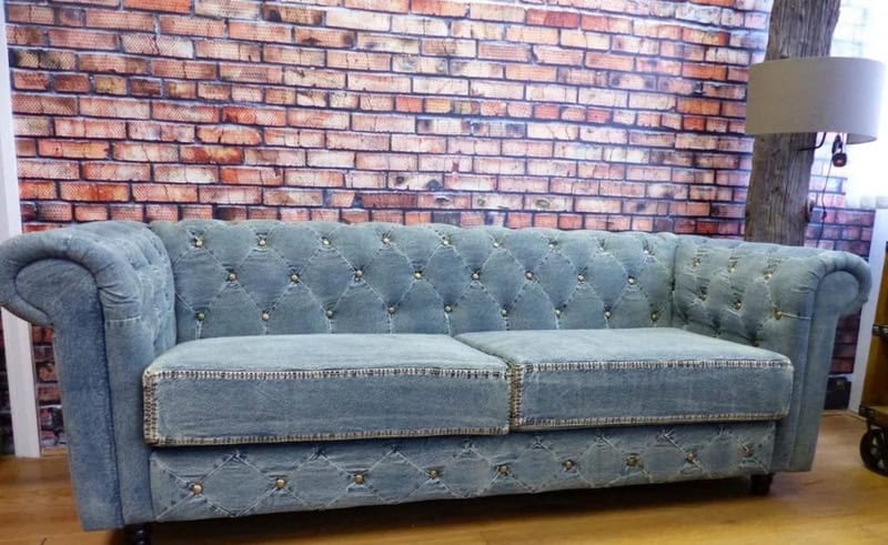 Vintage blue pleated jeans sofa with tufted design and wooden legs.