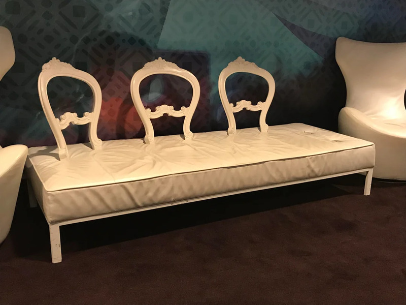 Elegant vintage white sofa with ornate backrest details and curved armrests.