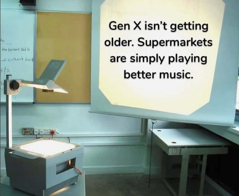 Classroom projector displaying a meme about Gen X and music.