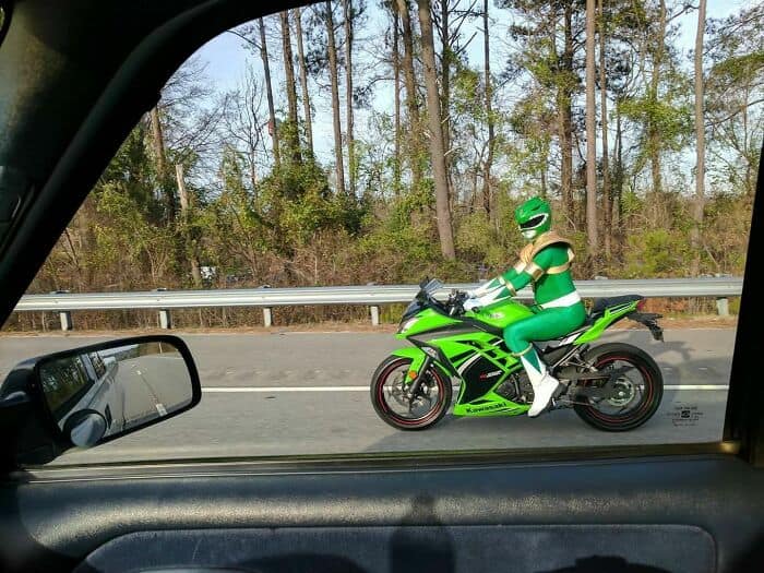 Green Power Ranger in costume riding a motorcycle on the highway.
