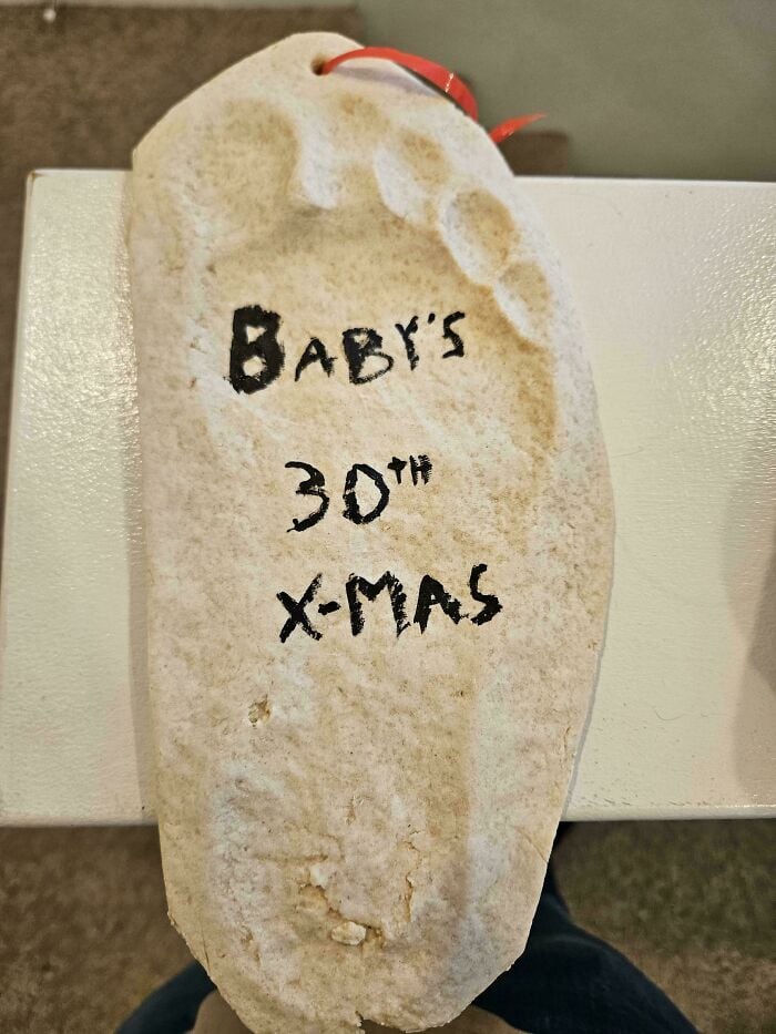 Festive baby sock with handwritten "Baby's 30th X-Mas" message for holiday humor.